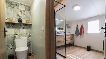 Un baño con ducha, inodoro y tocador con espejo.