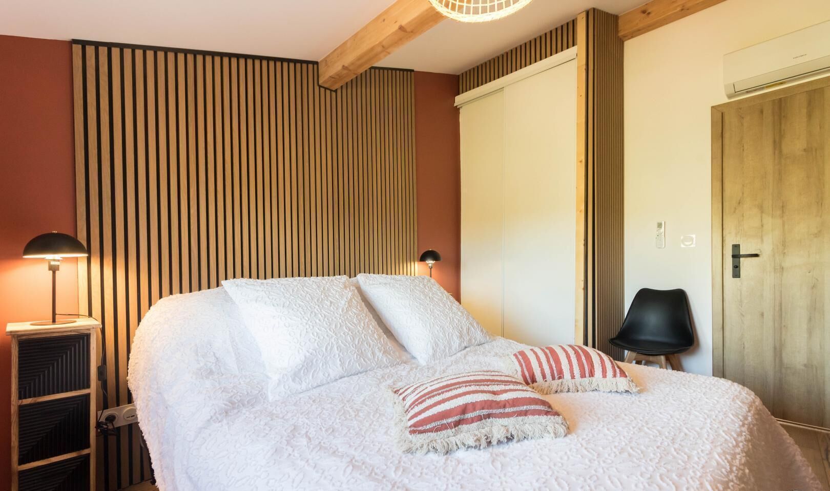 Ein Schlafzimmer mit einem Bett, einem Nachttisch, einer Lampe, einem Sessel und einem Kleiderschrank.