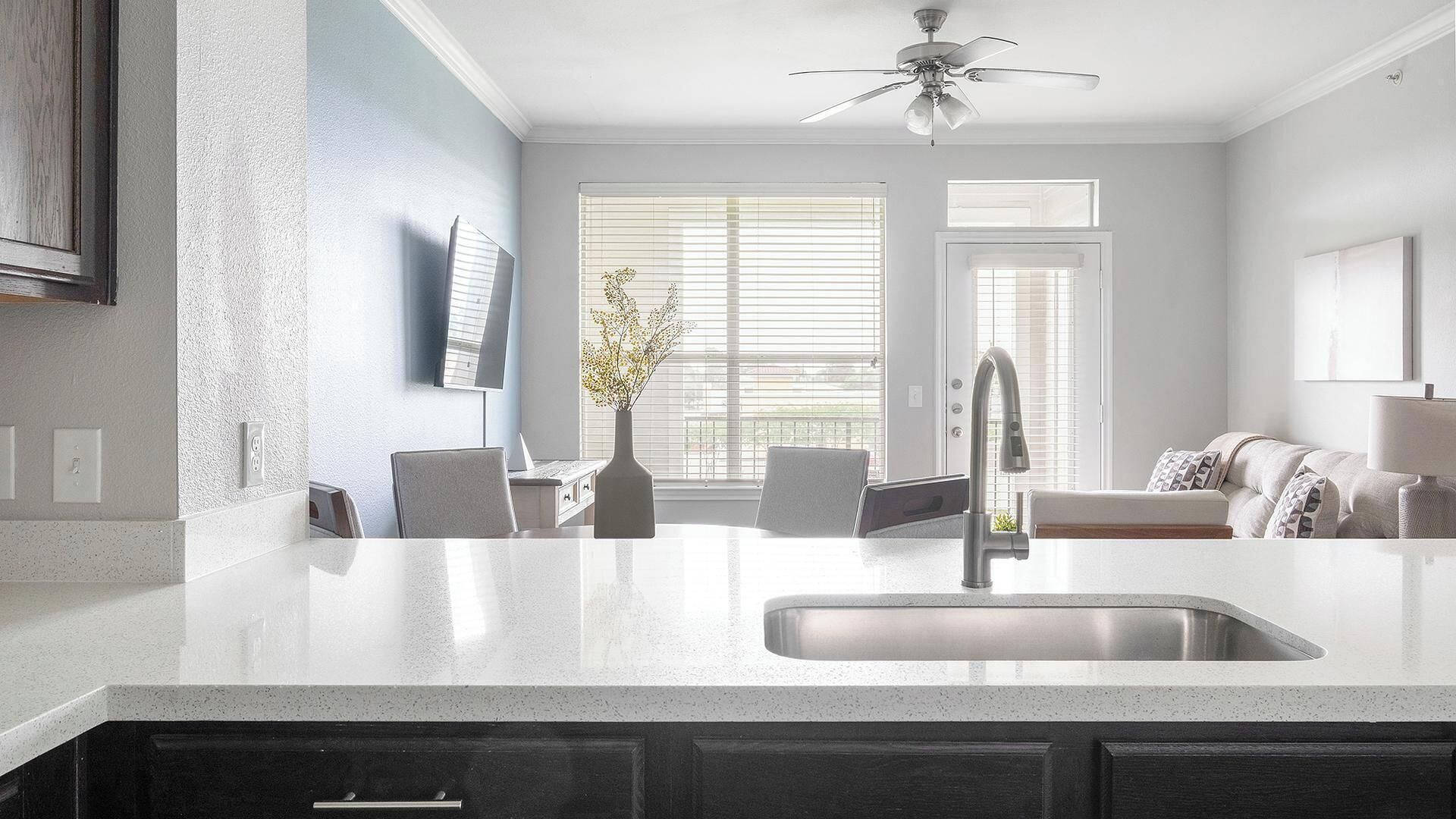 A modern kitchen with a white countertop, a built-in sink, and a ceiling fan.