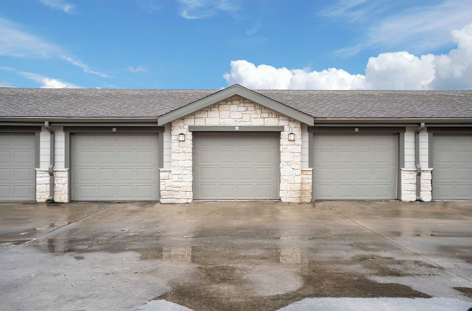 A building with three garage doors, a stone facade, and a clear sky.