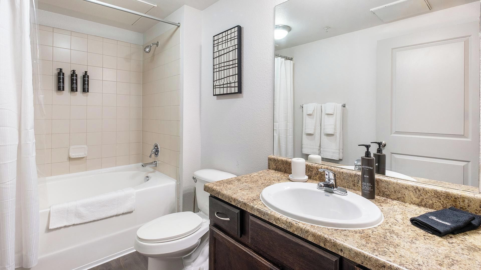 A bathroom with a bathtub, toilet, sink, and a large mirror.