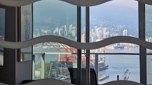 A modern office space with large windows overlooking a cityscape and a bridge. - Mountain View l Gym, Patio & Parking, 5 mins to DT (Vancouver)
