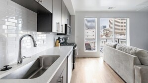 Una cocina moderna con azulejos blancos tipo metro, electrodomésticos de acero inoxidable y un amplio ventanal con vistas a la ciudad.