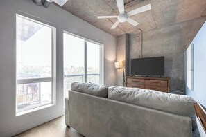 A modern living room with a large sofa, a flat-screen TV, and a ceiling fan. - Landing | Amazing Studio in Central City (Salt Lake City)