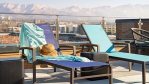 Een terras op het dak met lounge stoelen, een hoed en een deken.