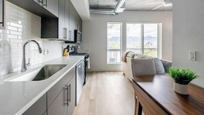 Een moderne keuken met een groot raam, een eethoek met een houten tafel en een bank.