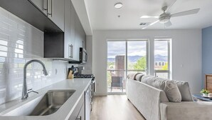 Et moderne køkken med en stor ø, et spiseområde med sofa og en balkon med udsigt.