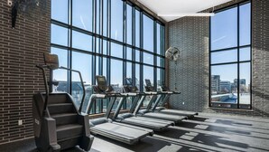 Et fitnesscenter med løbebånd, stair climber og store vinduer med udsigt over byen.