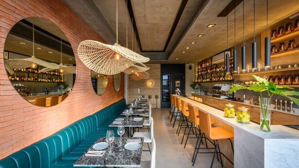 A restaurant with a long counter, bar seating, and a brick wall. - ROSSI TINY (Villa Mercedes)