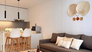 A modern living room with a sofa, a coffee table, and a dining area with chairs and a table. - ROSSI TINY (Villa Mercedes)