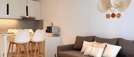 A modern living room with a sofa, a coffee table, and a dining area with chairs and a table.