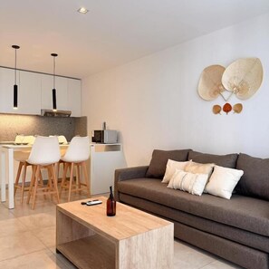A modern living room with a sofa, a coffee table, and a dining area with chairs and a table. - ROSSI TINY (Villa Mercedes)