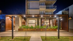 A modern building with a covered outdoor area, a gas station, and a restaurant named 'CHITO' in the background. - ROSSI TINY (Villa Mercedes)