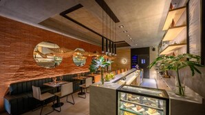 A modern interior with a brick wall, round mirrors, a bar area, seating, and a display case with desserts. - ROSSI TINY (Villa Mercedes)