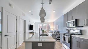 A modern kitchen with a central island, built-in appliances, and a view to the living area. - Landing | Chic 1BD in Central City (Salt Lake City)