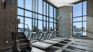 A gym with treadmills, a stair climber, and large windows offering a city view. - Landing | Chic 1BD in Central City (Salt Lake City)