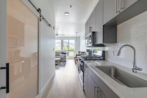 A modern kitchen with a stainless steel sink, a microwave, and a gas stove. - Landing | Amazing Studio in Central City (Salt Lake City)