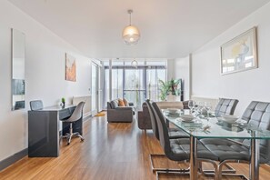 Ein modernes Wohnzimmer mit einem Glastisch, Ledersesseln, einer Couch und einem großen Fenster.