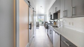 A modern kitchen with a central island, stainless steel appliances, and a view to the living area. - Landing | Spectacular Studio in Central City (Salt Lake City)