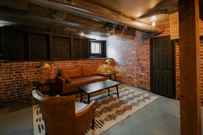 Ein Zimmer mit Backsteinwand, einer Couch, einem Couchtisch, einer Lampe und einer Tür.