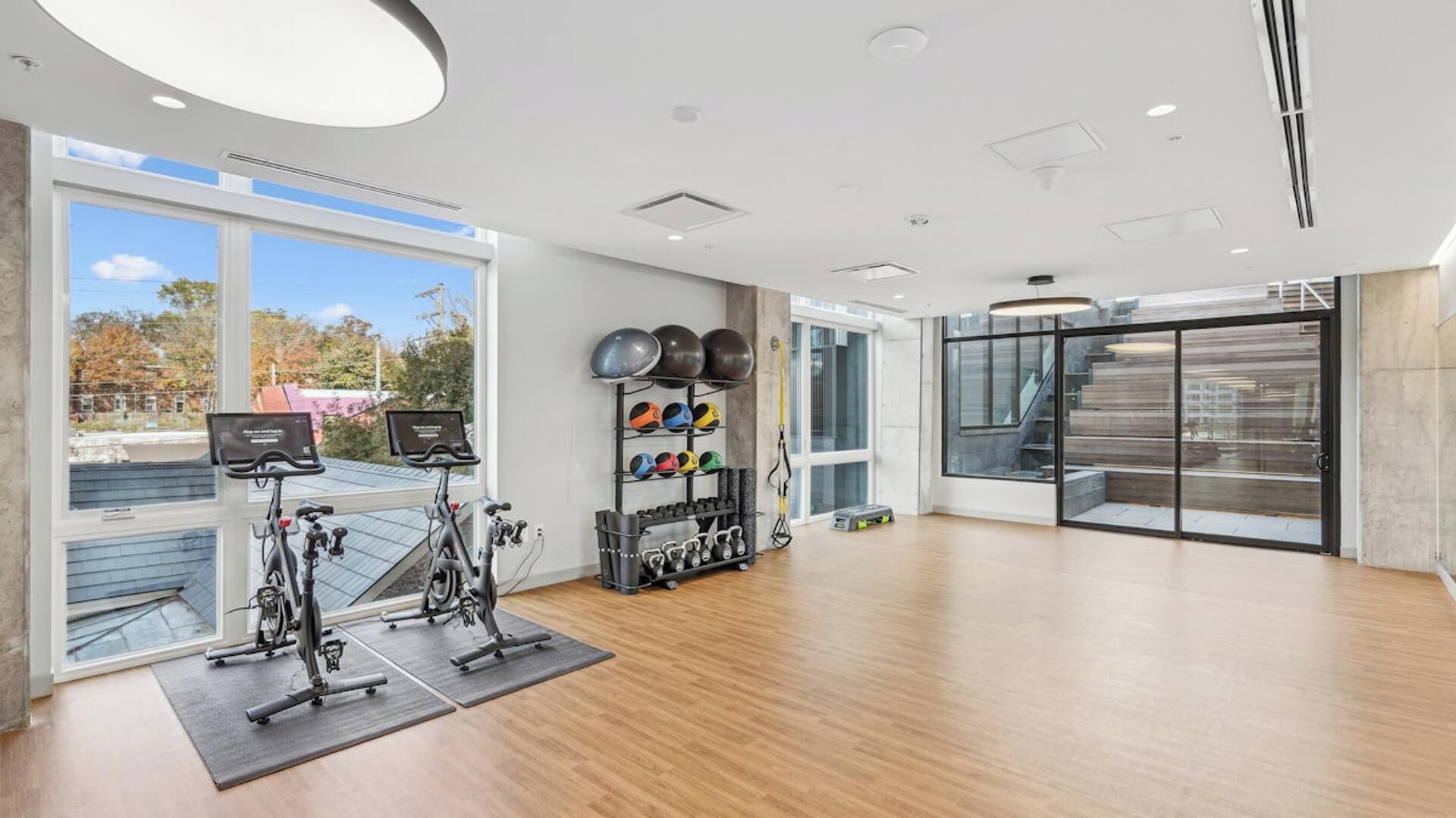Een moderne sportschool met trainingsfietsen, een rek met gewichten en een groot raam met uitzicht.