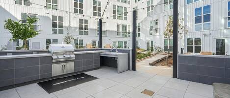 An outdoor kitchen area with a grill, sink, and outdoor seating.