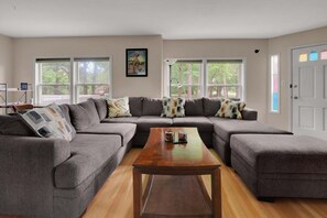 A living room with a sectional sofa, a wooden coffee table, and large windows. - Spacious 4-bedroom home in  Clarksville IN. accommodates 16.  gourmet kitchen.  (Clarksville)