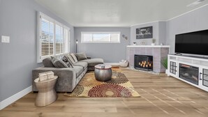 A living room with a grey sofa, a fireplace, a TV, and a patterned rug. - Merry Melly, The Midtown Charmer! Close to Midtown, downtown, freeway, airport (Reno)