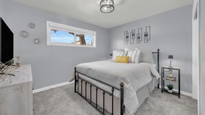 A bedroom with a bed, a nightstand, a lamp, a window, and a ceiling light fixture. - Merry Melly, The Midtown Charmer! Close to Midtown, downtown, freeway, airport (Reno)