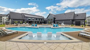 En swimmingpool med solstolar och en byggnad med modern design.