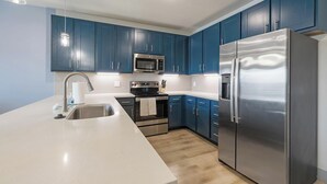 A modern kitchen with blue cabinets, stainless steel appliances, and a white countertop. - Landing | Beautiful 1BD in Grand Prairie (Grand Prairie)