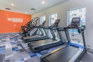 Ein Fitnessstudio mit Laufbändern, einer Wand mit dem Schriftzug 'THE GIBSON' und Blick auf Gebäude im Freien.
