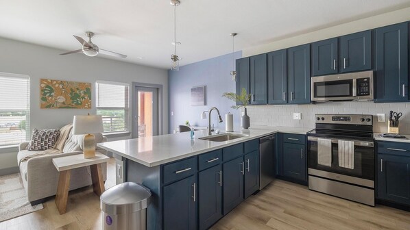 A modern kitchen with dark blue cabinets, stainless steel appliances, and a white countertop. - Landing | Stunning 1BD in Grand Prairie (Grand Prairie)