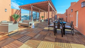 A rooftop terrace with a pergola, outdoor seating, and a view of the cityscape. - Landing | Chic 2BD in Grand Prairie (Grand Prairie)