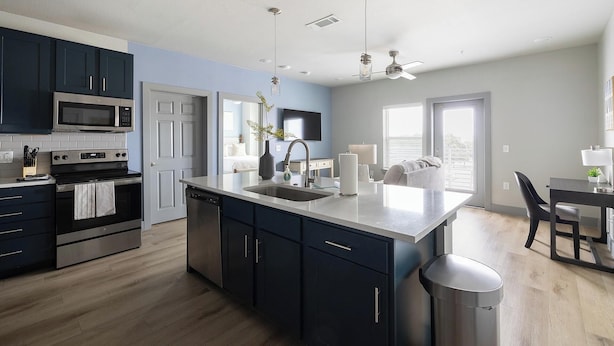 A modern kitchen with dark cabinets, stainless steel appliances, and a central island. - Landing | Stunning 2BD in Grand Prairie (Grand Prairie)