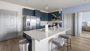 A modern kitchen with a central island, stainless steel appliances, and dark blue cabinets. - Landing | Stunning 2BD in Grand Prairie (Grand Prairie)
