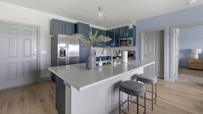 A modern kitchen with a central island, stainless steel appliances, and blue cabinetry. - Landing | Stunning 2BD in Grand Prairie (Grand Prairie)
