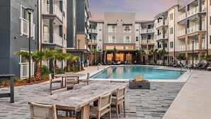 A modern apartment complex with a swimming pool, outdoor seating, and a fire pit. - Landing | Stylish 1BD, Pool, Rooftop Lounge (Bellview)
