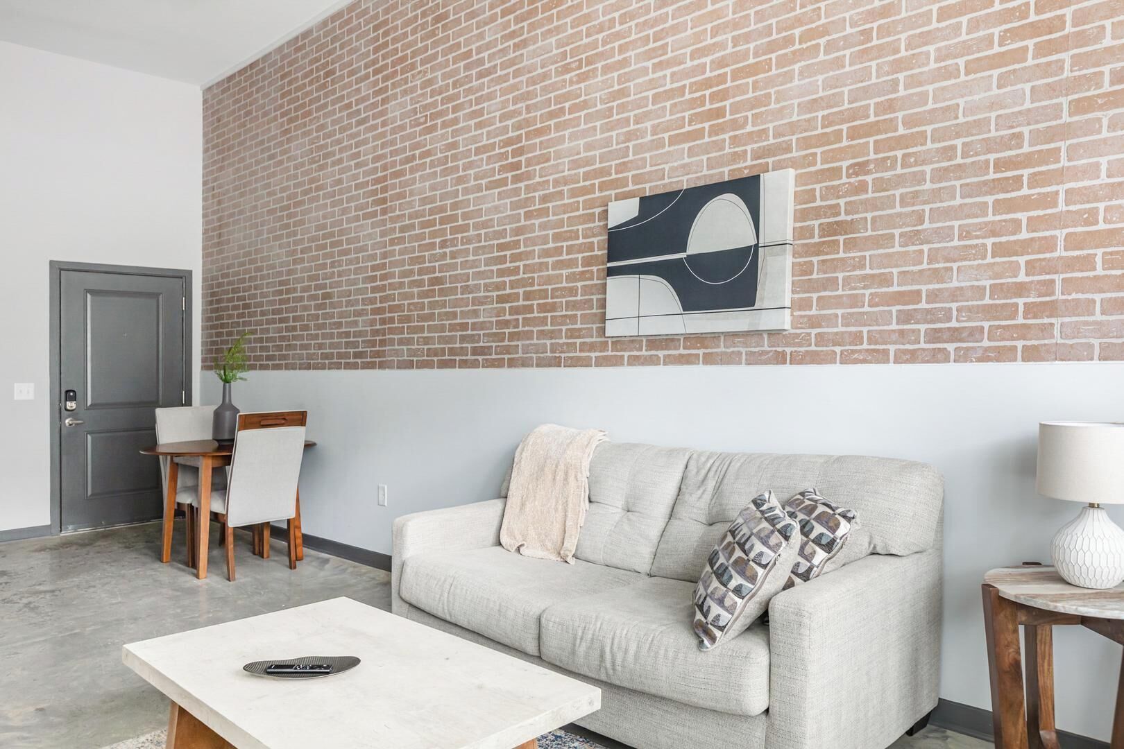 Ein Wohnzimmer mit Backsteinwand, einer Couch, einem Couchtisch, einer Lampe und einem Gemälde.