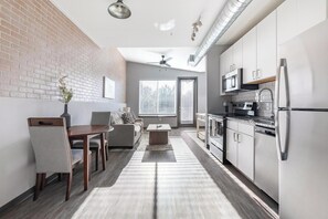 A modern kitchen with white cabinets, a stainless steel refrigerator, and a microwave. - Landing | Stylish 1BD, Pool, Gym (Bellview)