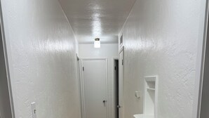 Ein Flur mit weißen Wänden, Holzboden und einer Tür am Ende.