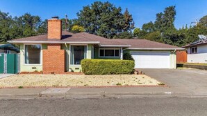 Einbungalow mit Garage, Schornstein und einem gepflegten Vorgarten.