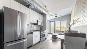 Eine moderne Küche mit Edelstahlgeräten, weißen Schränken und einem Essbereich mit Holztisch und -stühlen.