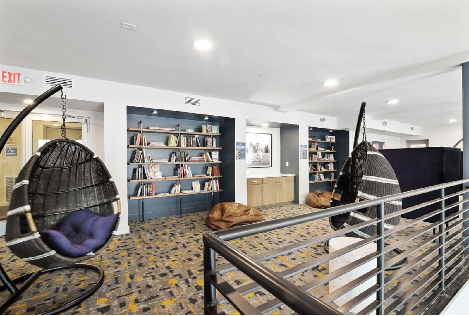 Eine moderne Bibliothek mit Hängehängestühlen, Bücherregalen und einer Treppe.