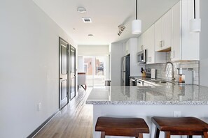 A modern kitchen with white cabinets, a granite countertop, and a stainless steel refrigerator. - Landing | Incredible 2BD, Gym, Rooftop Lounge (Bellview)