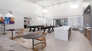 Et rummeligt, moderne køkken med en central ø, spiseområde med stole og et billardbord.