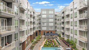 A multi-story residential building with balconies, a central courtyard with a pool, and outdoor seating. - Landing | Beautiful Studio in Bricktown (Fort Worth)