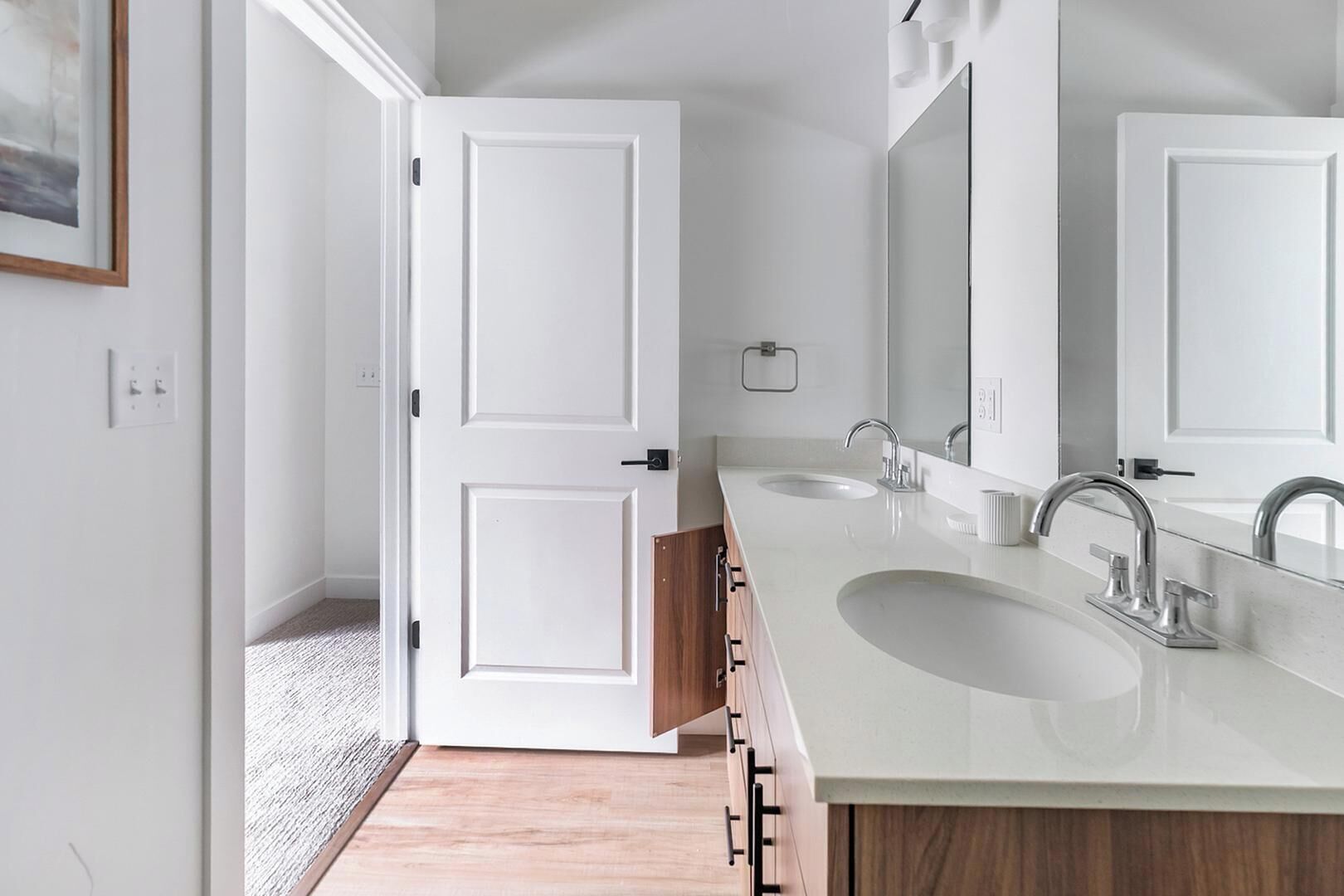 Un bany modern amb un lavabo doble, mobles de fusta i un mirall gran.
