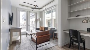 A modern living space with a sofa, a coffee table, a desk, and a chair. - Landing | Modern 1BD, Gym (Austin)