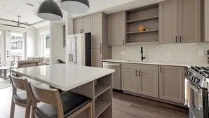 Een moderne keuken met een centraal eiland, roestvrijstalen apparatuur en lichte houten keukenkastjes.